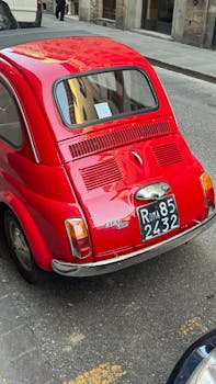 Vintage red Fiat parked on a Floransa street in sunny Tuscany, Italy.