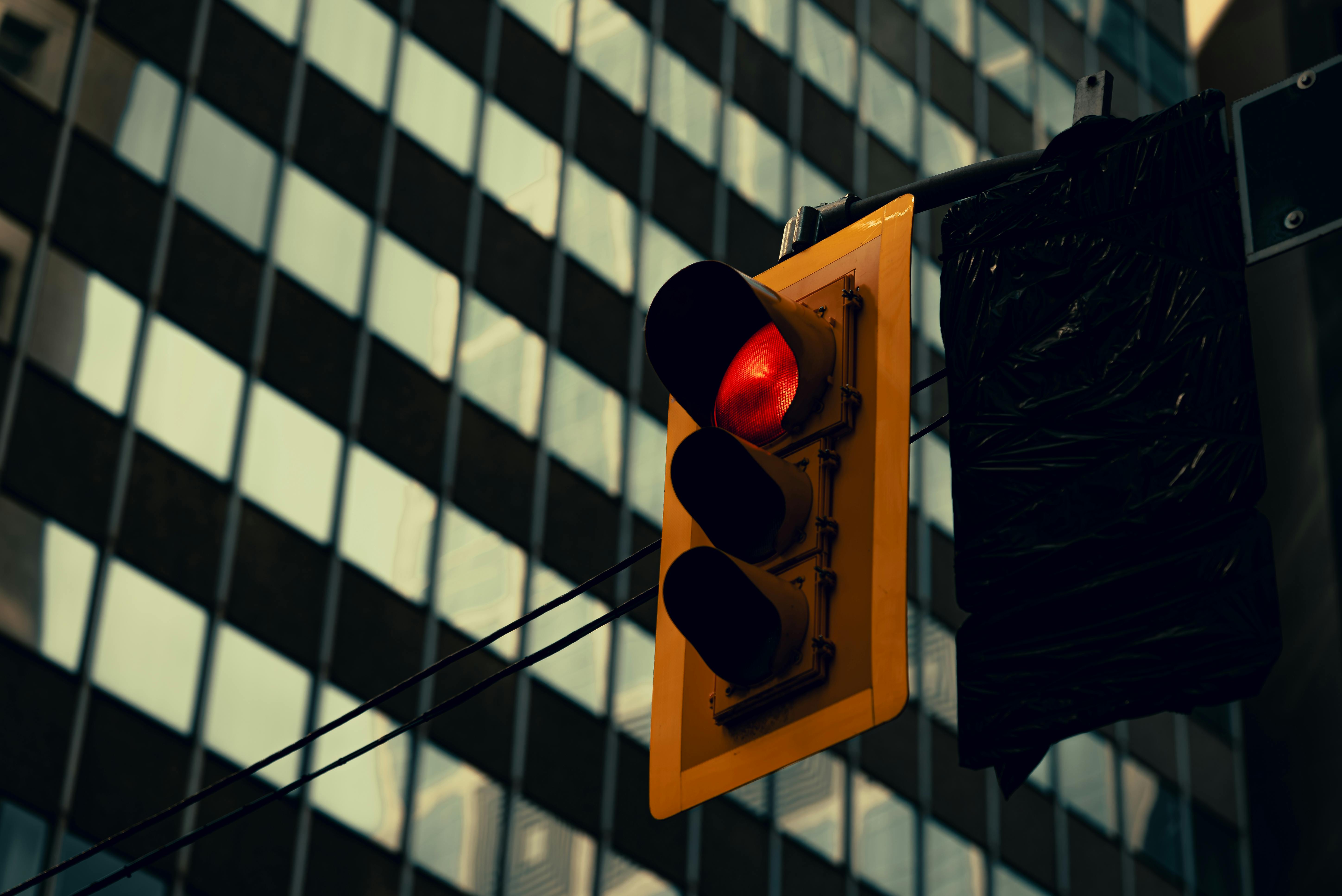 A red traffic light against a background of glass buildings in an urban setting.