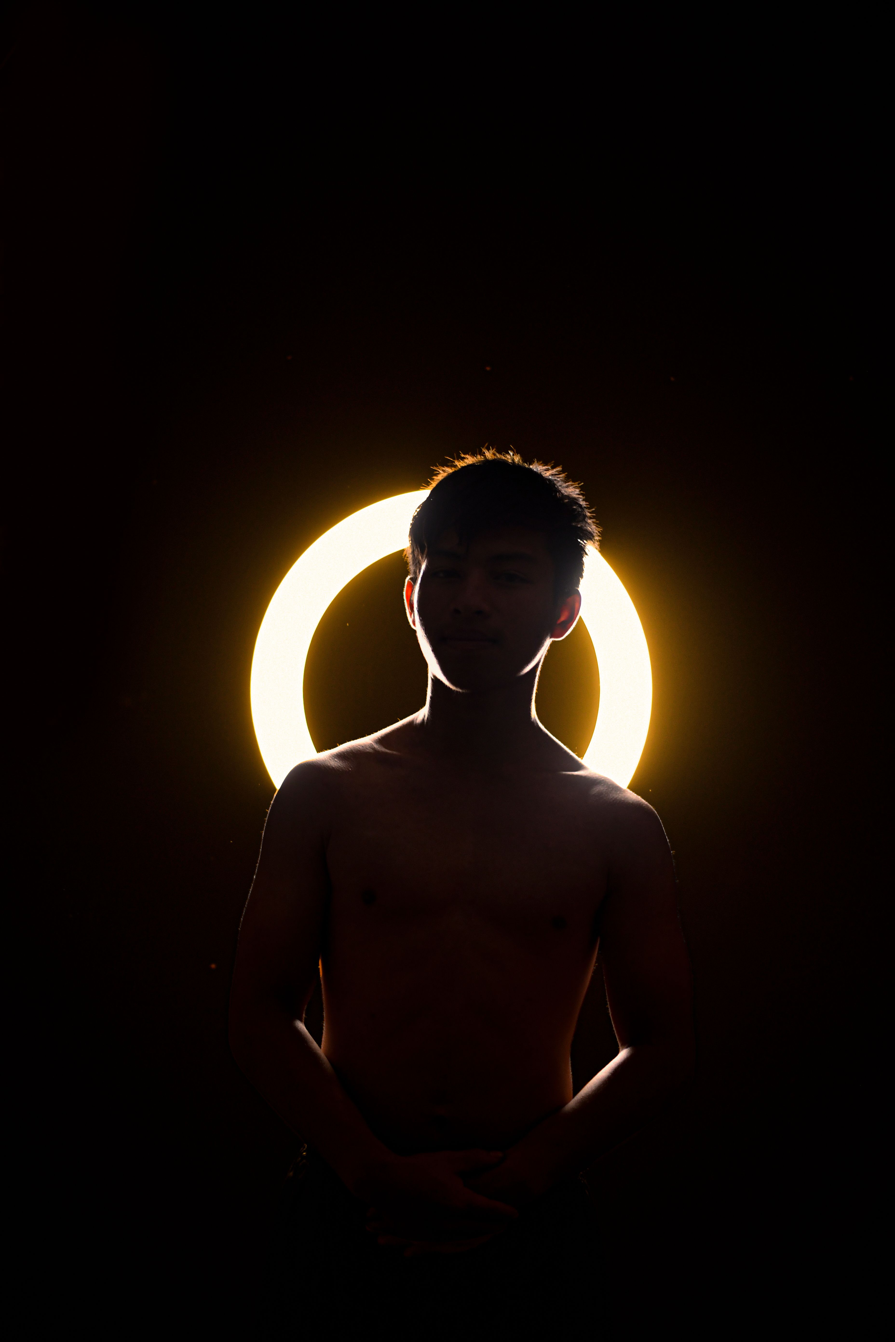 Silhouette of a man against a glowing halo light, creating dramatic contrast.
