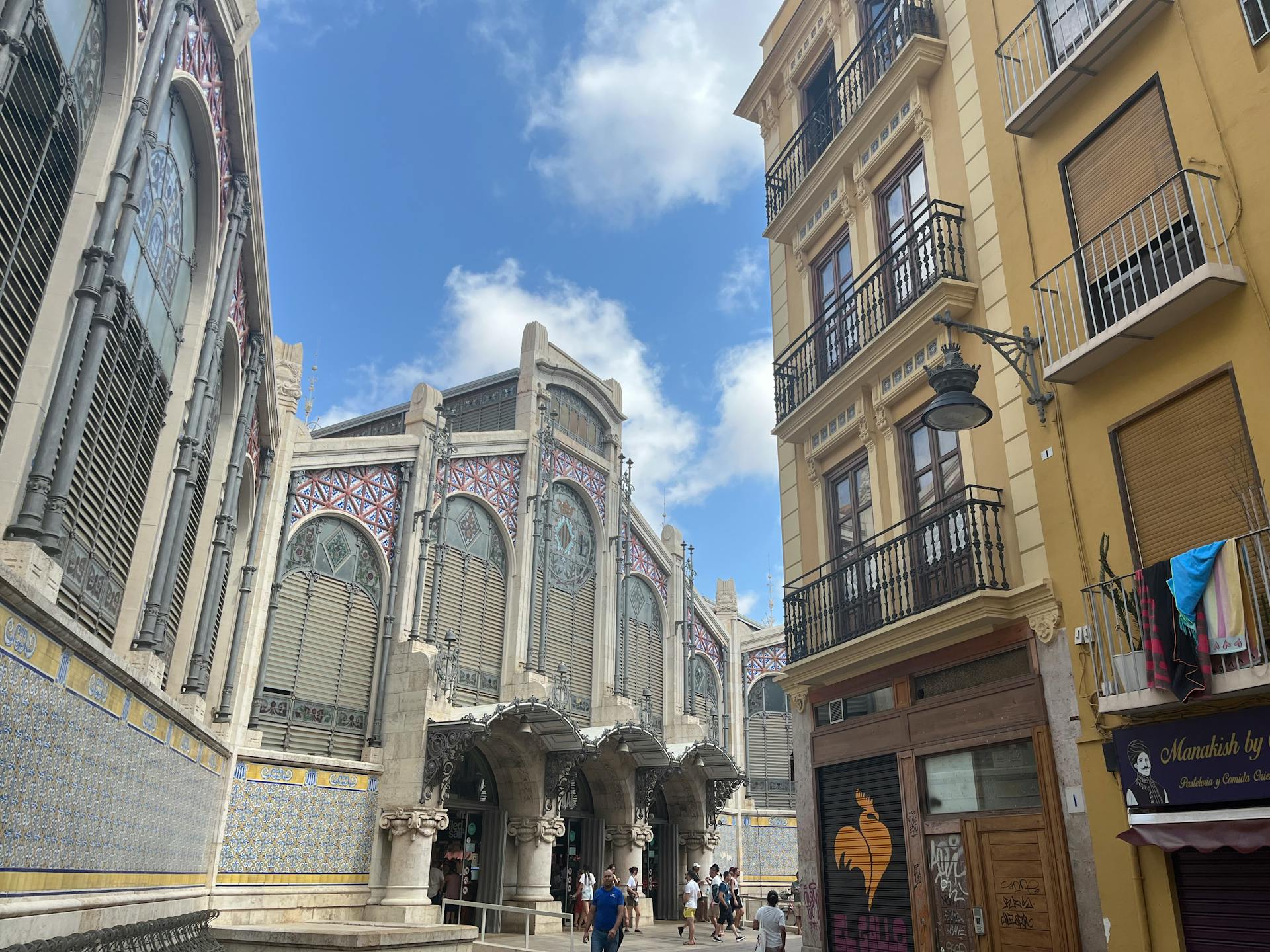 Street view of València's Central Market with historic buildings under a blue sky.