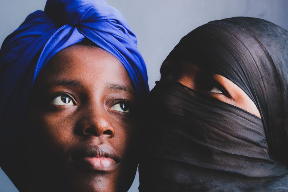 A compelling portrait of two women wearing vibrant and traditional headscarves, portraying cultural diversity and expression.