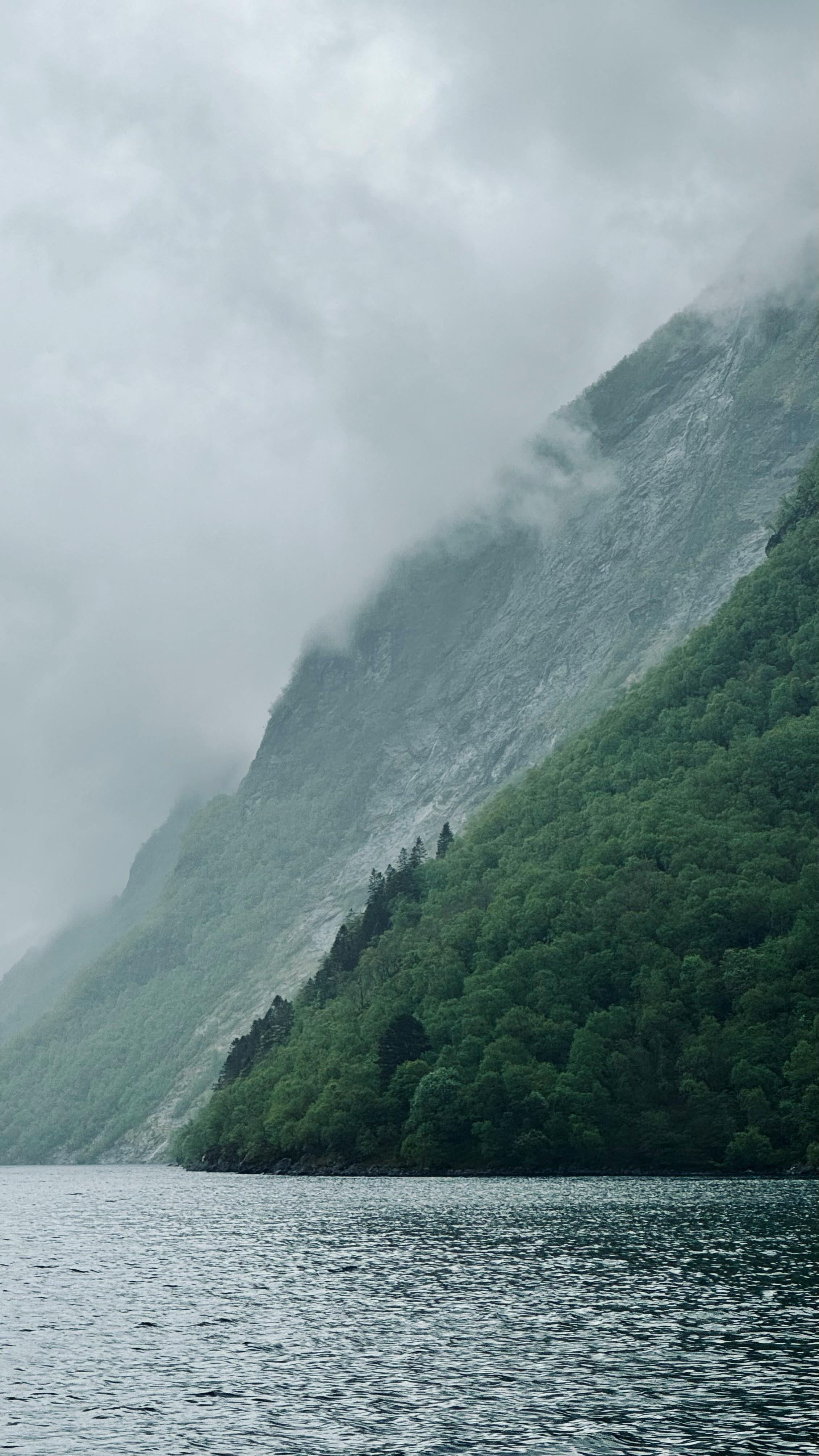 Tranquil view of a mist-covered mountain and lake in Ålesund, perfect for nature and travel enthusiasts.