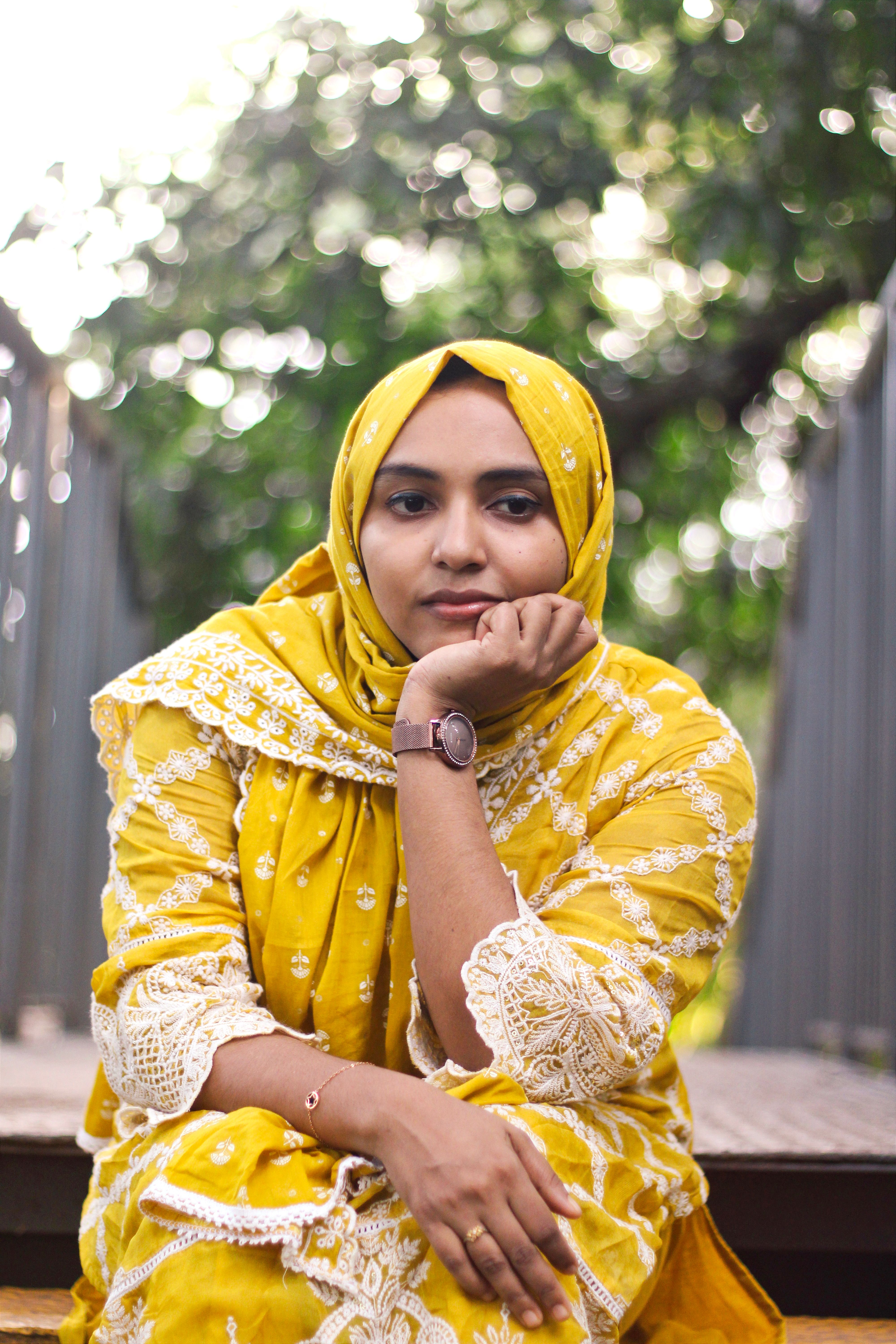 A captivating portrait of a woman in traditional yellow dress outdoors in Nilambur, India.