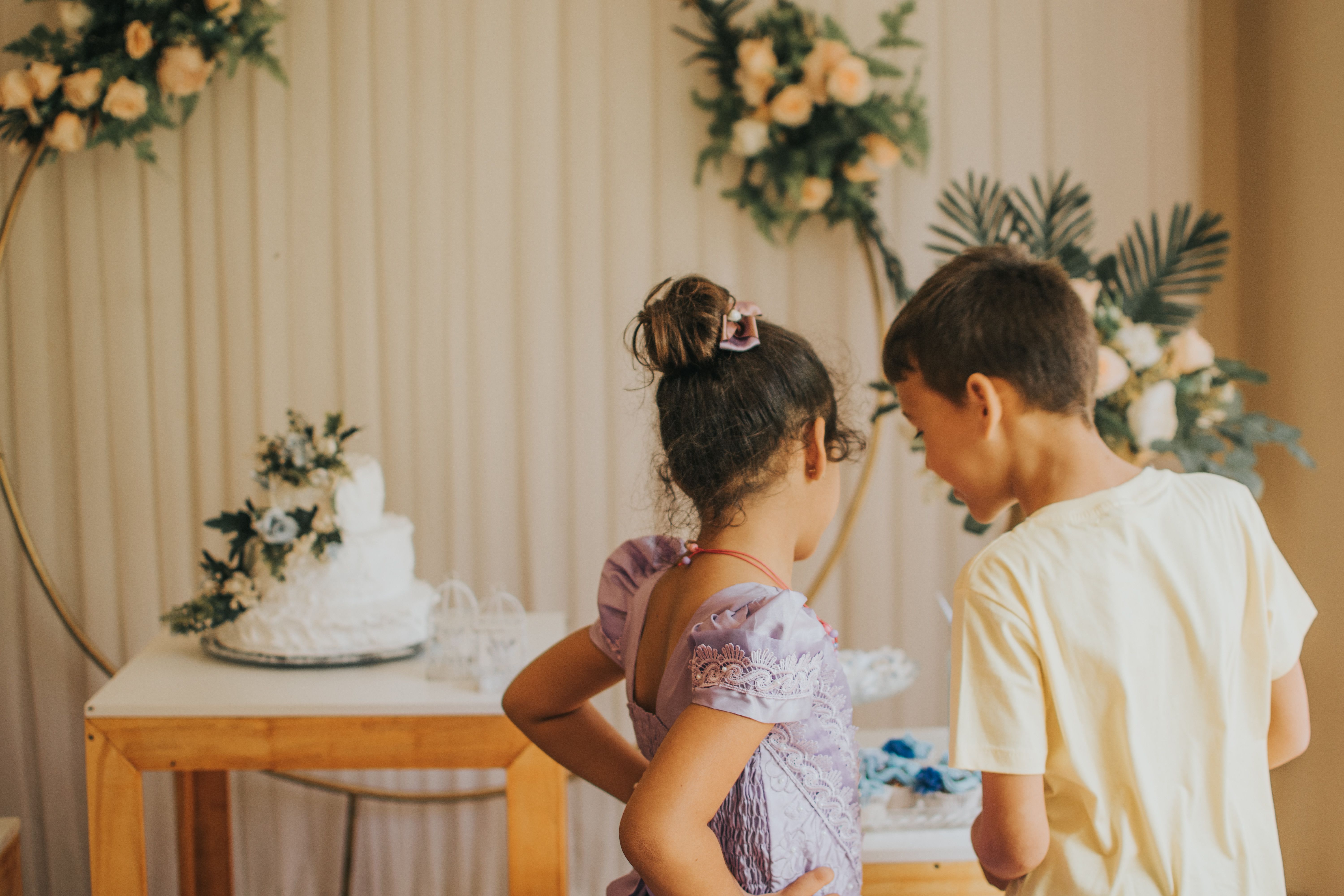 Two children in conversation at a beautifully decorated wedding reception.
