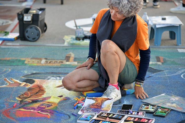 A Woman Sitting On The Ground With A Chalk Drawing