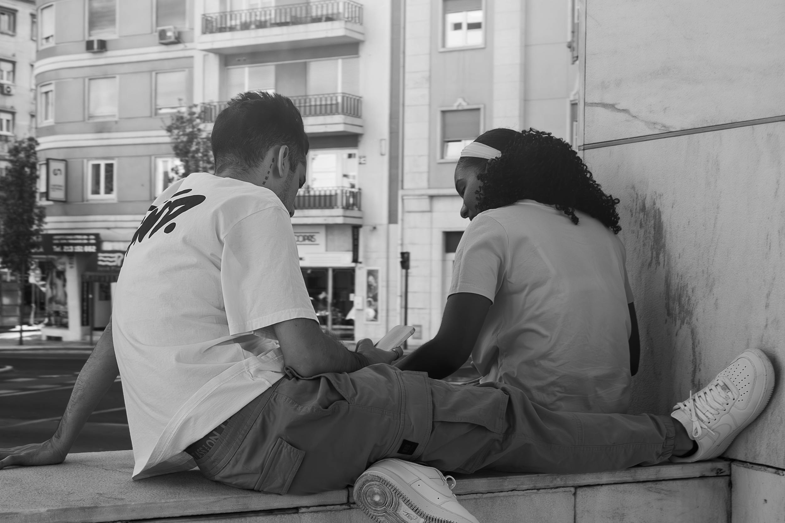 two people sitting on a ledge talking to each other