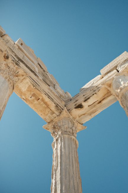 A stunning view of ancient stone columns reaching into a clear blue sky, symbolizing architectural beauty.