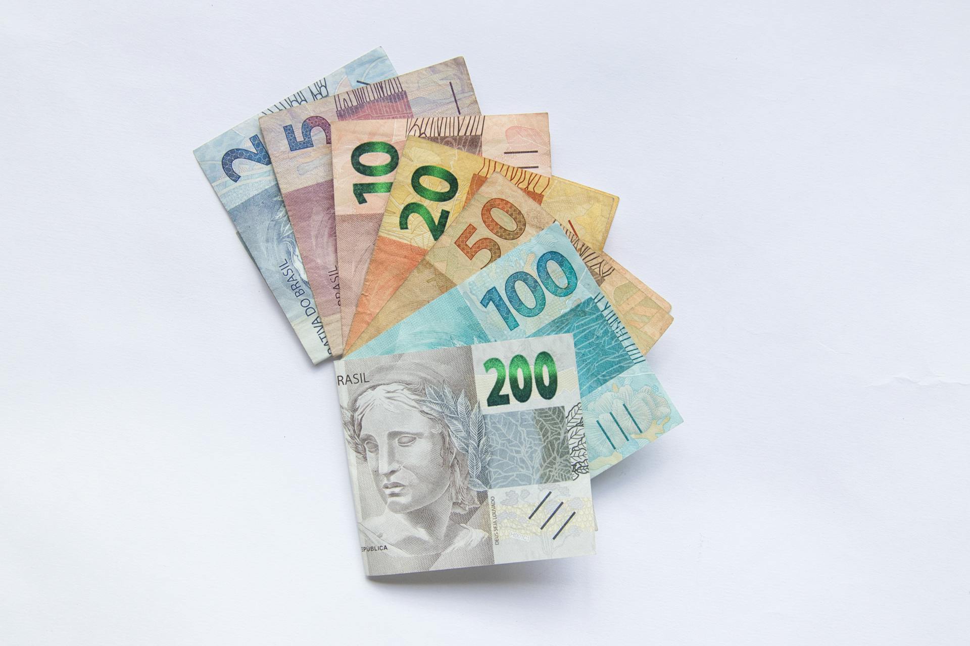 A fan arrangement of colorful Brazilian Real banknotes on a white background showcasing different values.