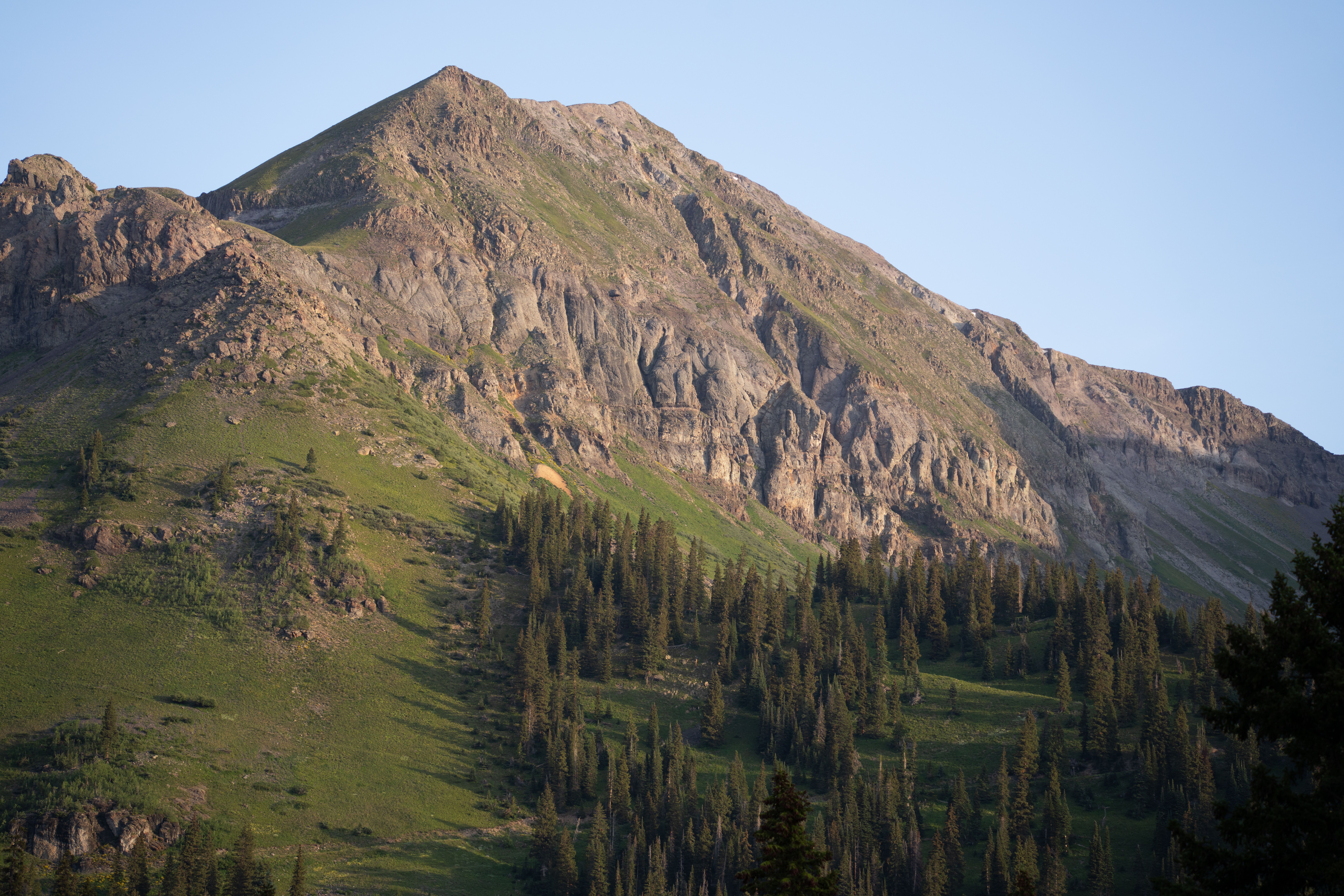 A mountain with a green peak and pine trees · Free Stock Photo