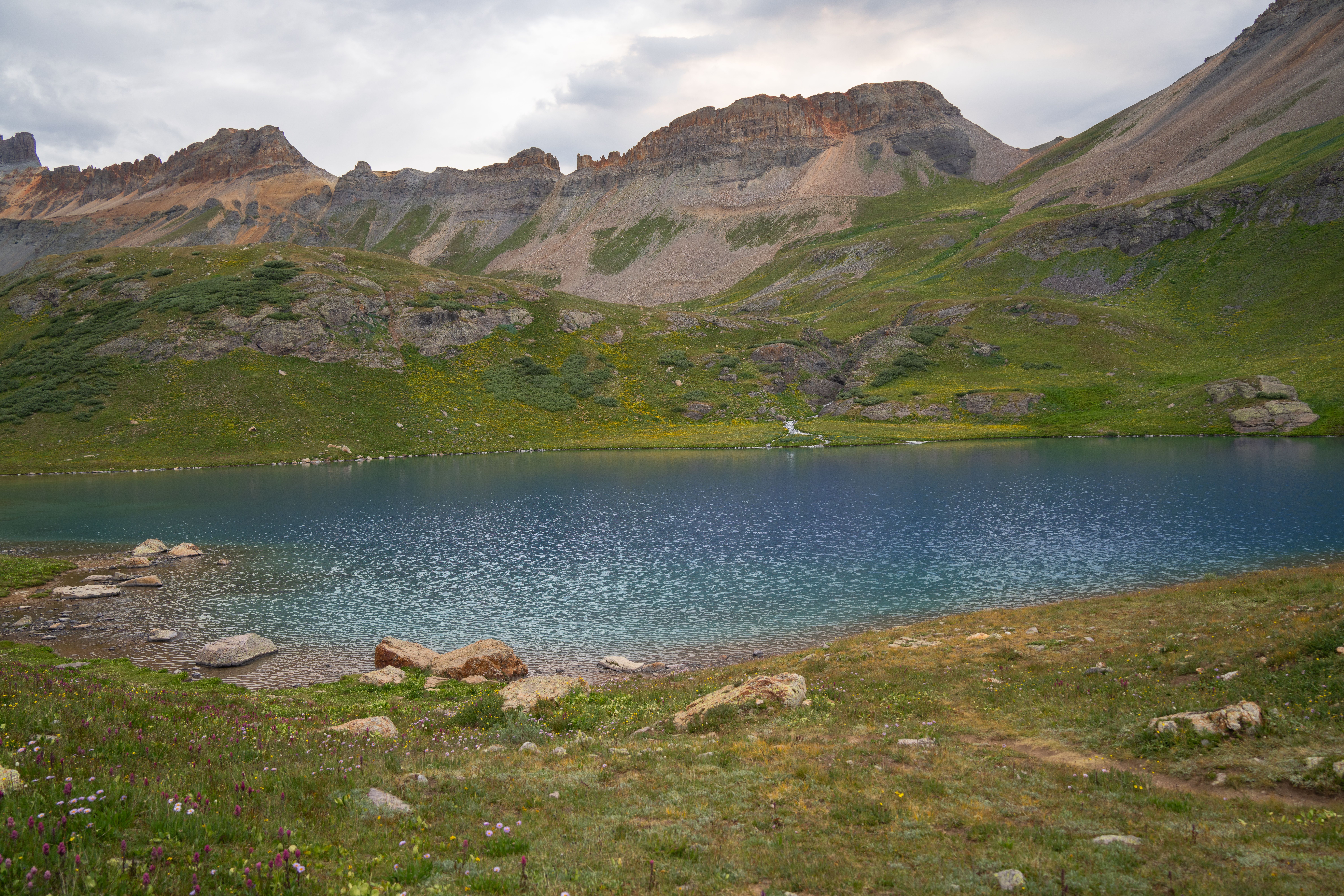A mountain lake with grass and rocks in the foreground · Free Stock Photo