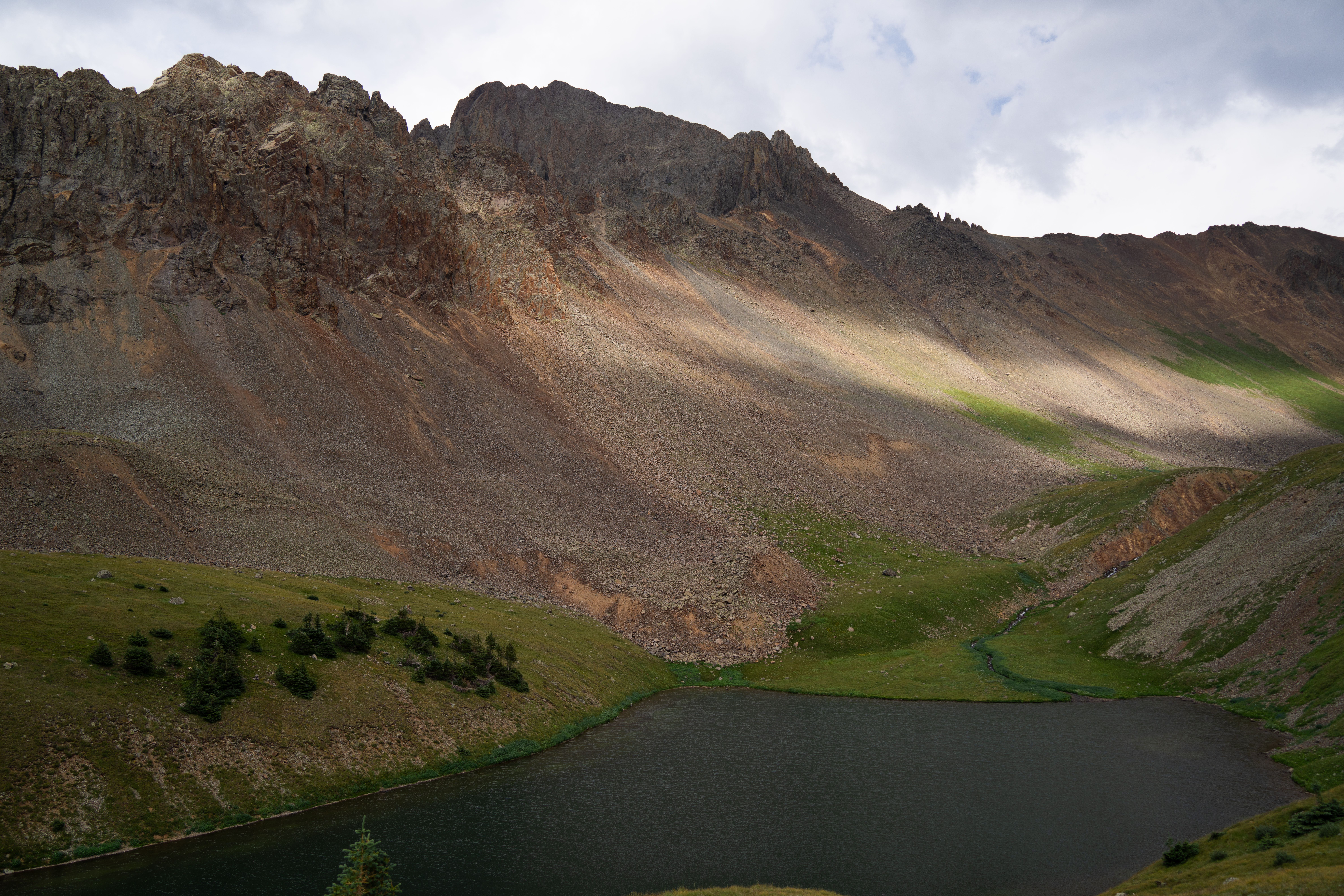 Explore the serene mountain lake and rugged peaks in San Juan National Forest.