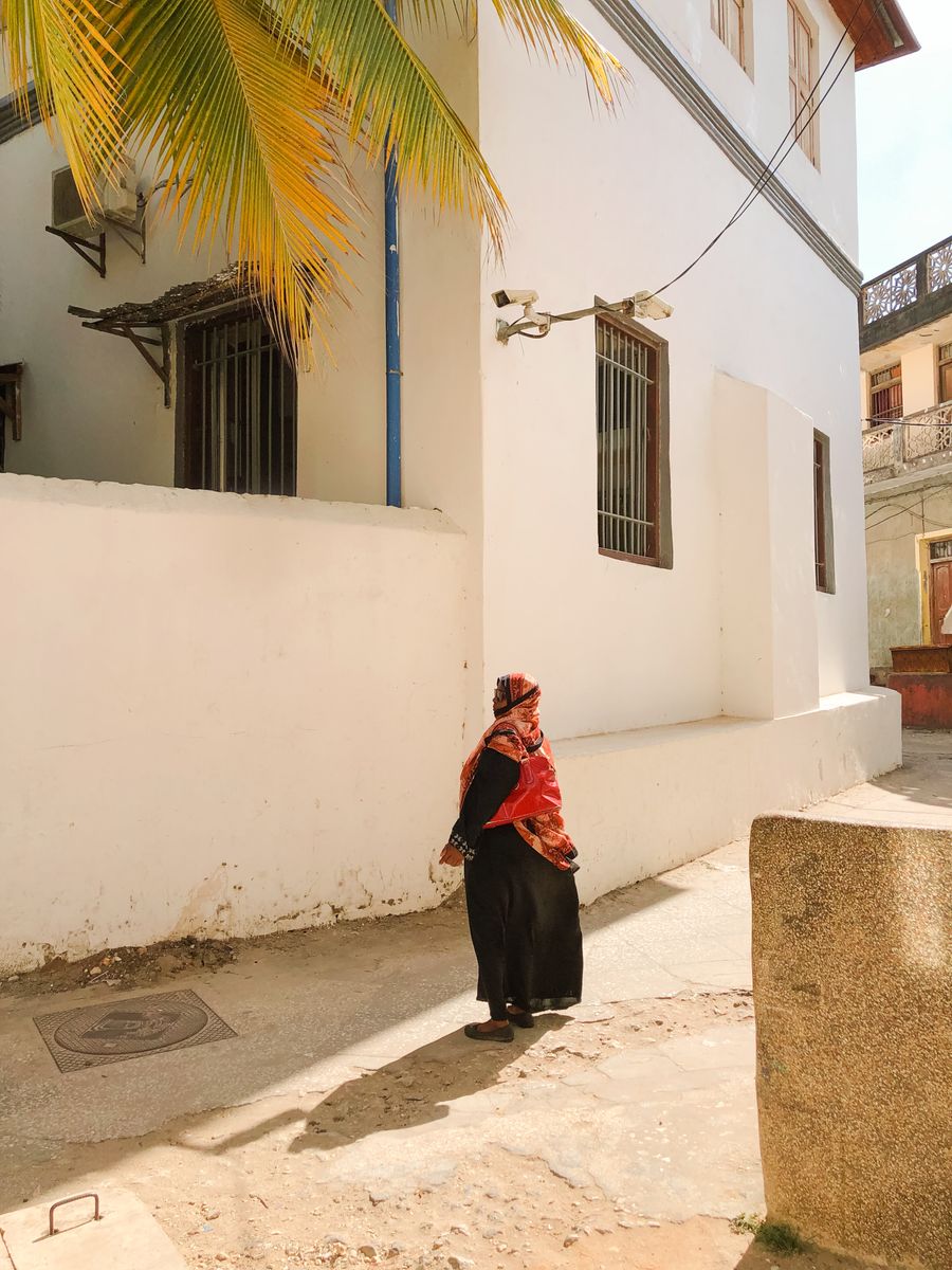 A woman walking down a sunlit alley in Stone Town, Zanzibar