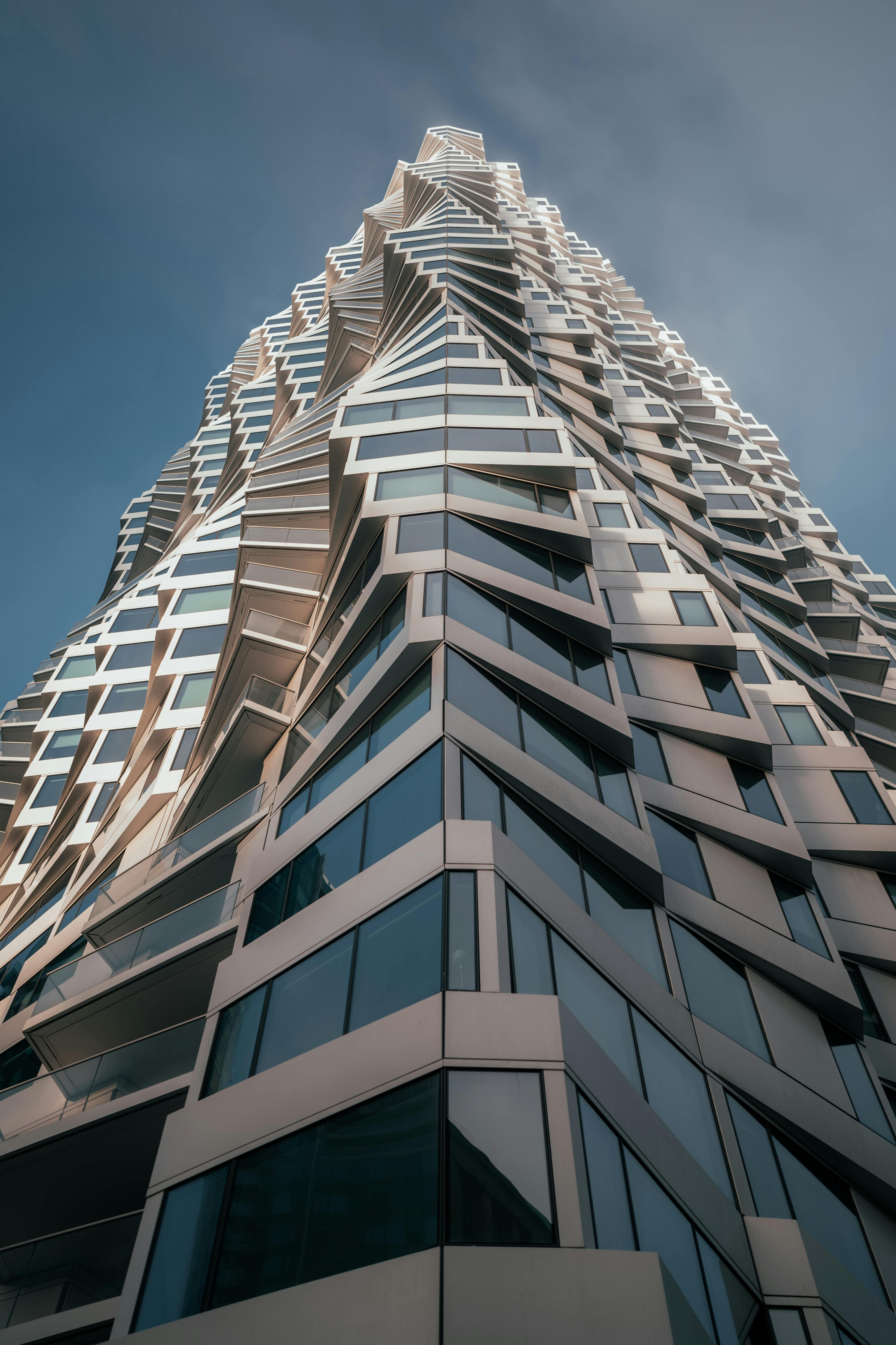 A modern skyscraper featuring a dynamic and twisted facade design in an urban setting.