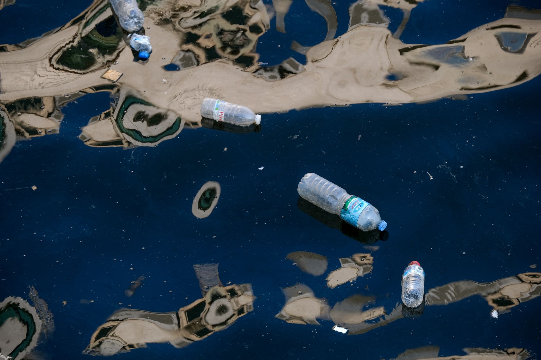 Plastic bottles floating in dark polluted water illustrating environmental pollution.