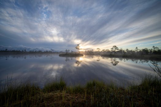 Tranquil dawn scene with misty lake reflections and dramatic sky, perfect for nature enthusiasts.