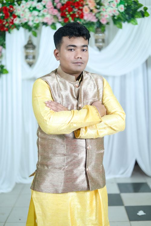 Free Portrait of a young man in traditional attire against a floral backdrop. Stock Photo
