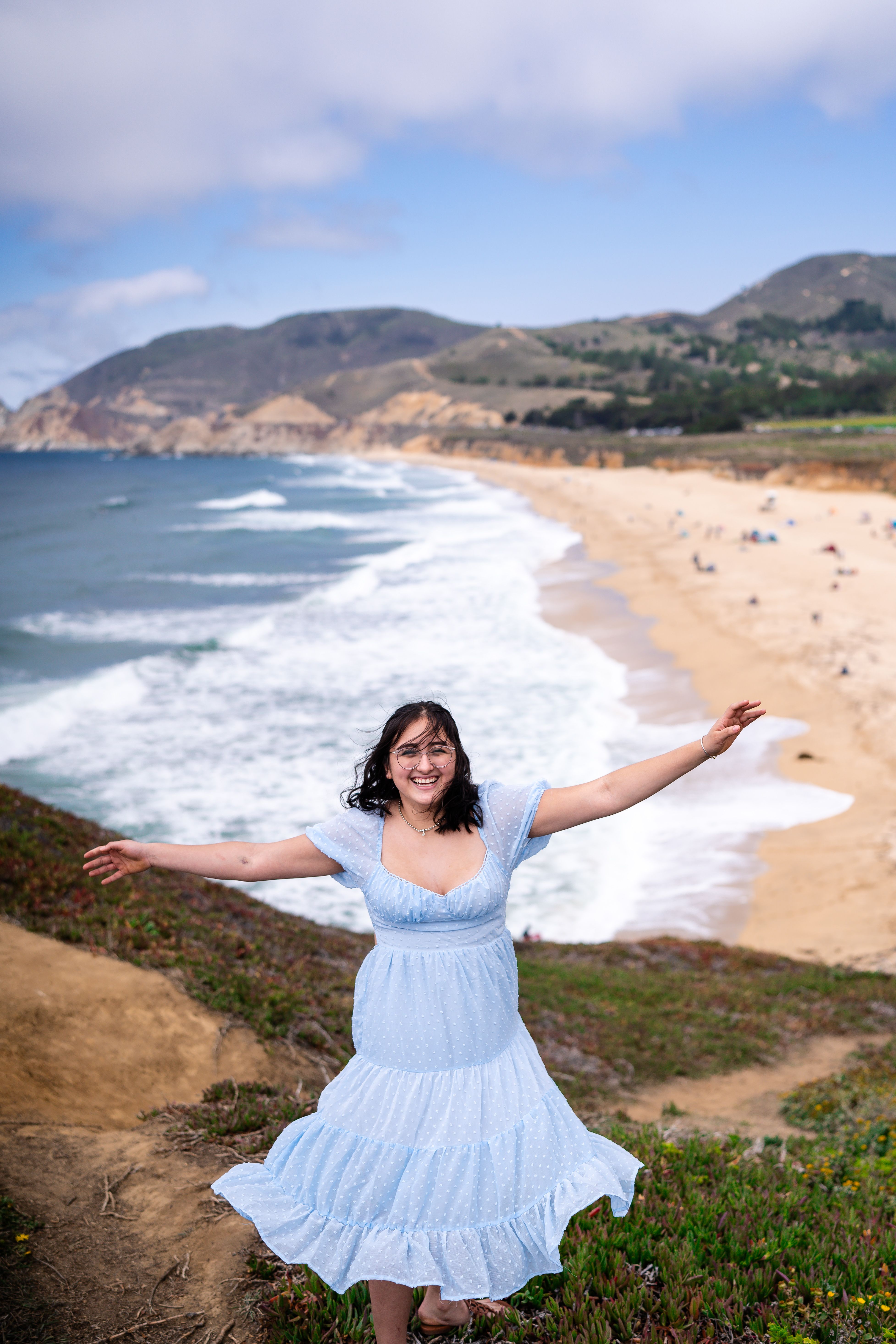 A woman in a blue dress standing on a beach  Free Stock Photo