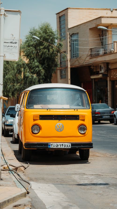 Free A classic yellow Volkswagen van is parked on an urban street, reflecting vintage style. Stock Photo