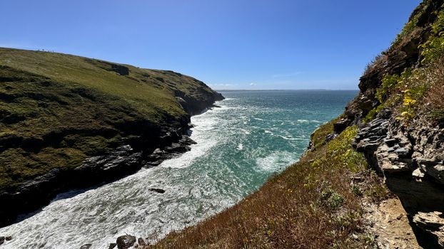 Scenic view of the rugged coastline at Tintagel, England under a clear blue sky.