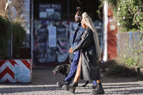 Free Trendy couple with dog on a sunny urban street in Berlin, showcasing fashionable attire. Stock Photo