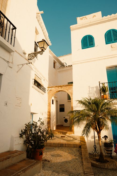 Free Picturesque whitewashed alleyway with vibrant blue accents in a Mediterranean town. Stock Photo