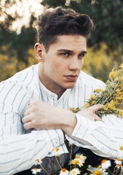 英俊男子穿着白衬衫，周围是野花