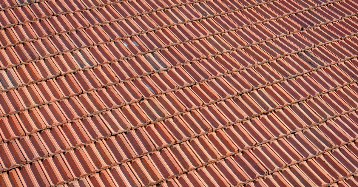 Aerial view of a textured red clay tile roof with a repeating pattern.