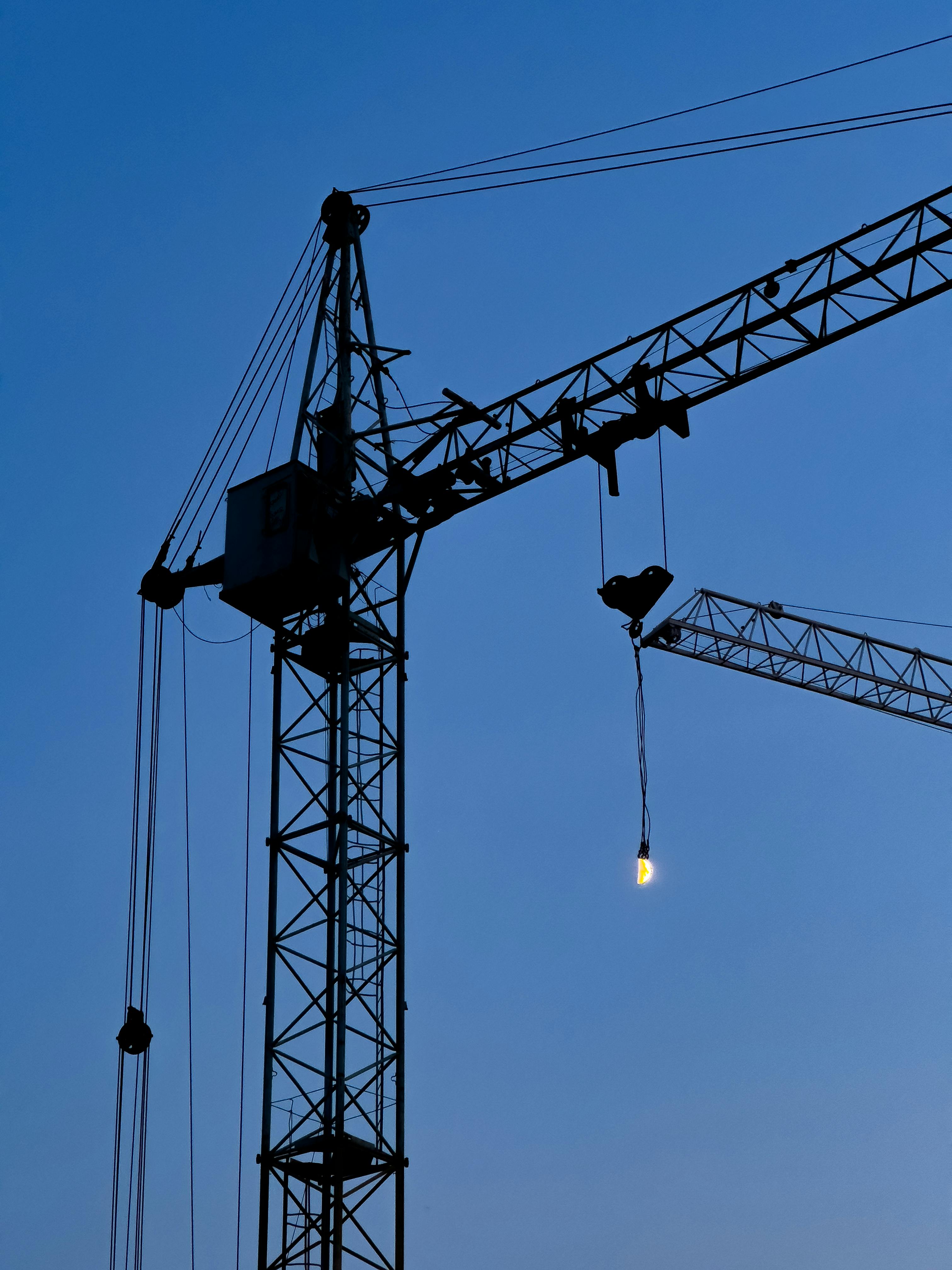Grayscale Photo of a Tower Crane Under Cloudy Sky · Free