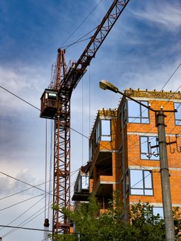 A detailed view of a crane and partially constructed building under a sunny sky.