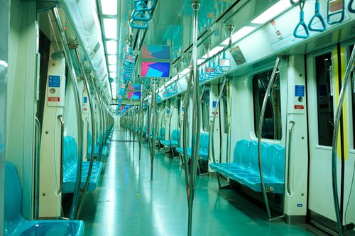 Free A well-lit, empty modern subway train interior showcasing blue seats and overhead handles. Stock Photo