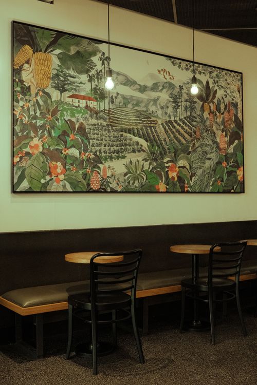 Free A cozy dining space featuring vibrant botanical wall art, wooden tables, and chairs. Stock Photo