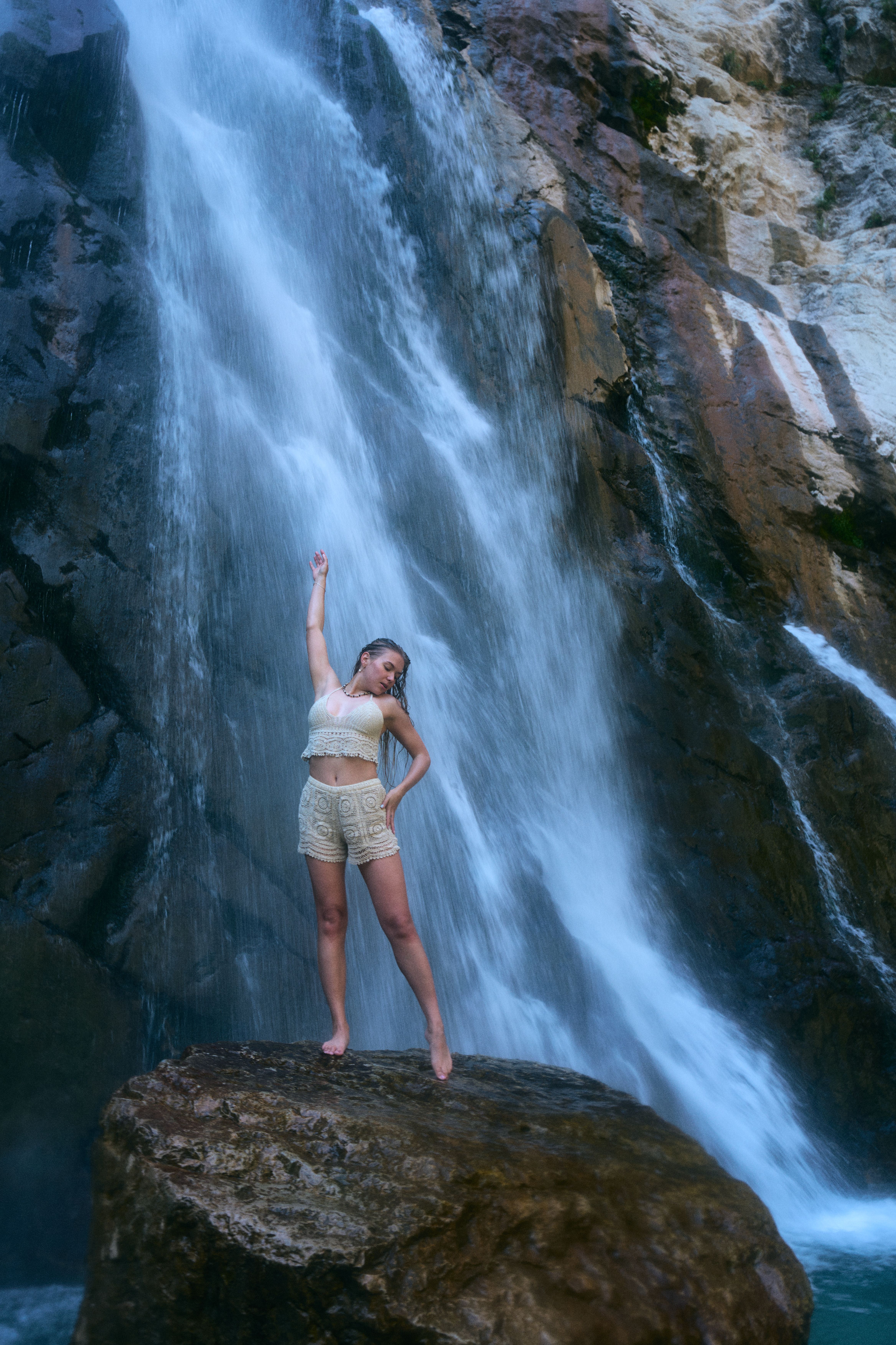 A woman standing on a rock in front of a waterfall · Free Stock Photo