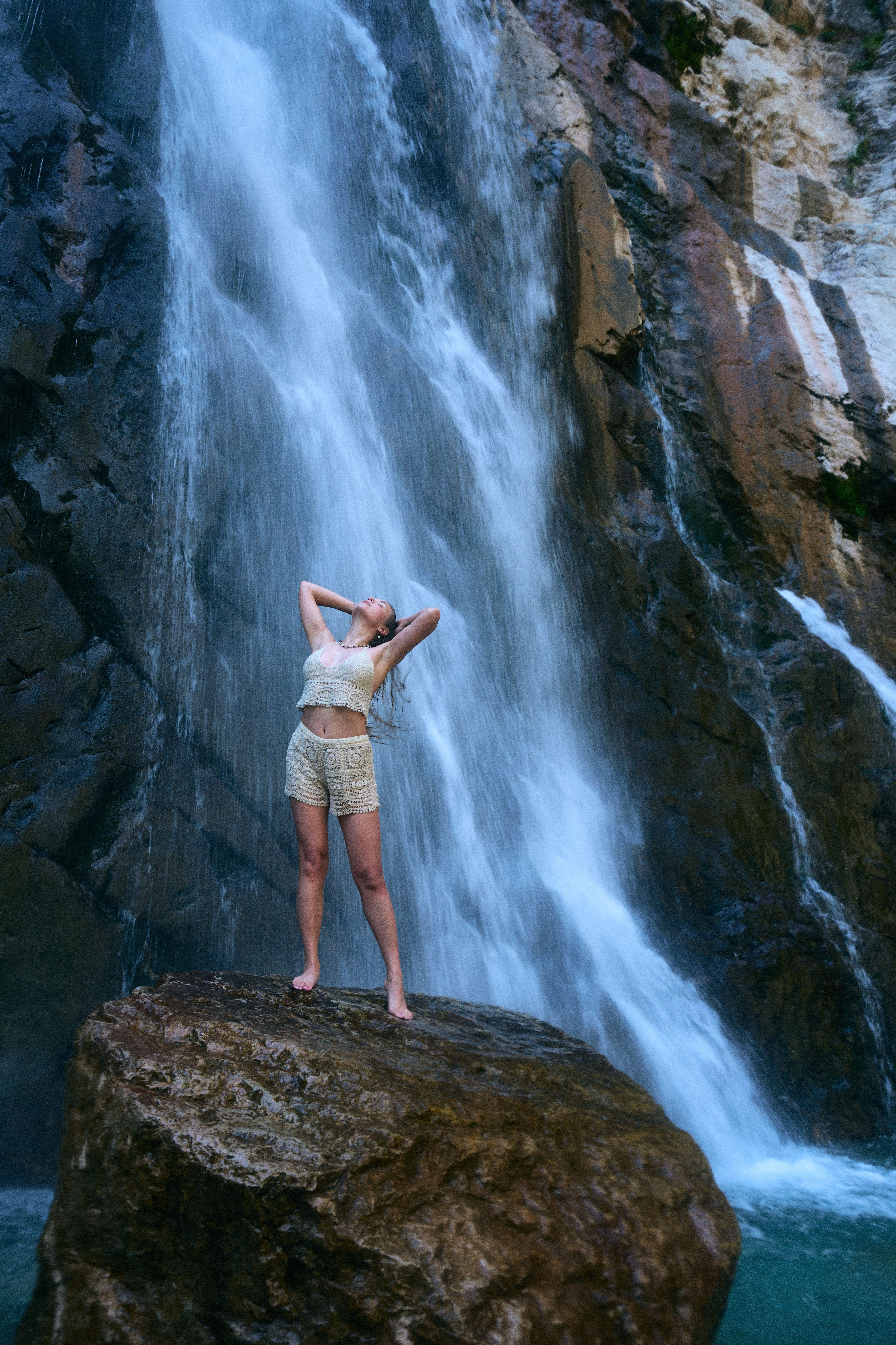 A woman standing on top of a rock in front of a waterfall · Free Stock ...