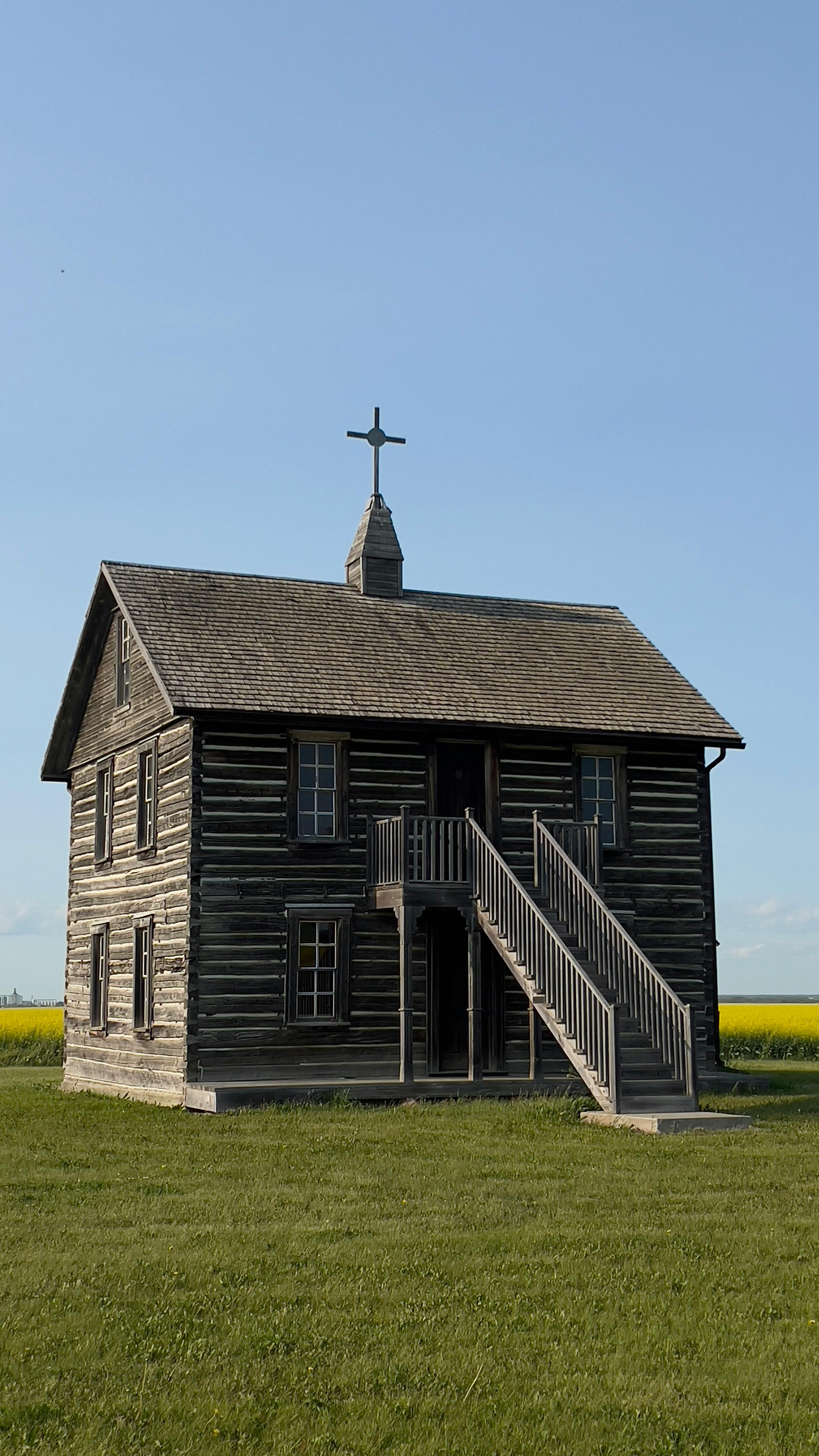 a small wooden church in the middle of a field