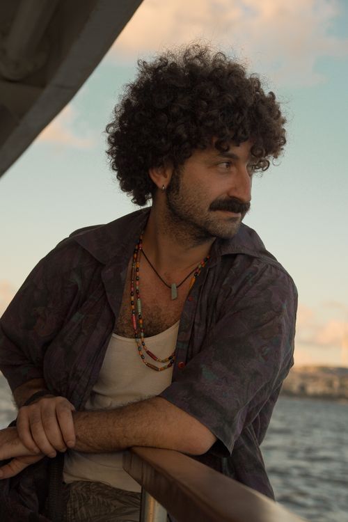 Free A man with curly hair enjoys a scenic sunset on a boat ride. Stock Photo