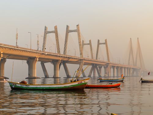 Free Picturesque view of the Bandra-Worli Sea Link during sunset with colorful boats in the foreground. Stock Photo