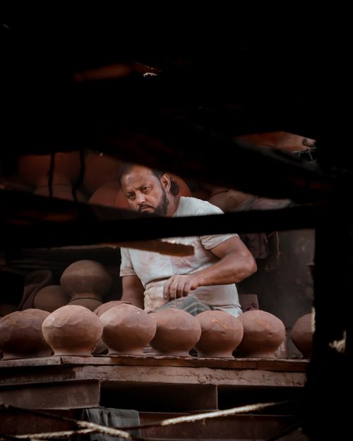Free Artisan carefully crafting clay pots in a dimly lit workshop with focused concentration. Stock Photo