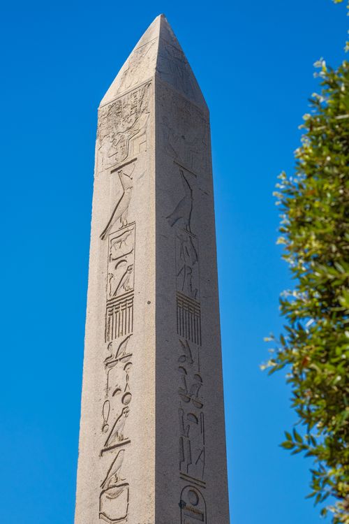 Free A tall ancient obelisk with hieroglyphics set against a clear blue sky. Stock Photo