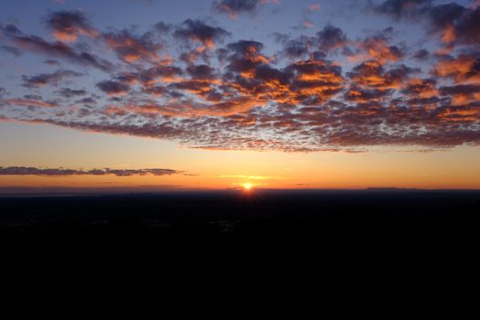 Stunning sunset with vibrant clouds over a dark horizon, perfect for travel and nature themes.