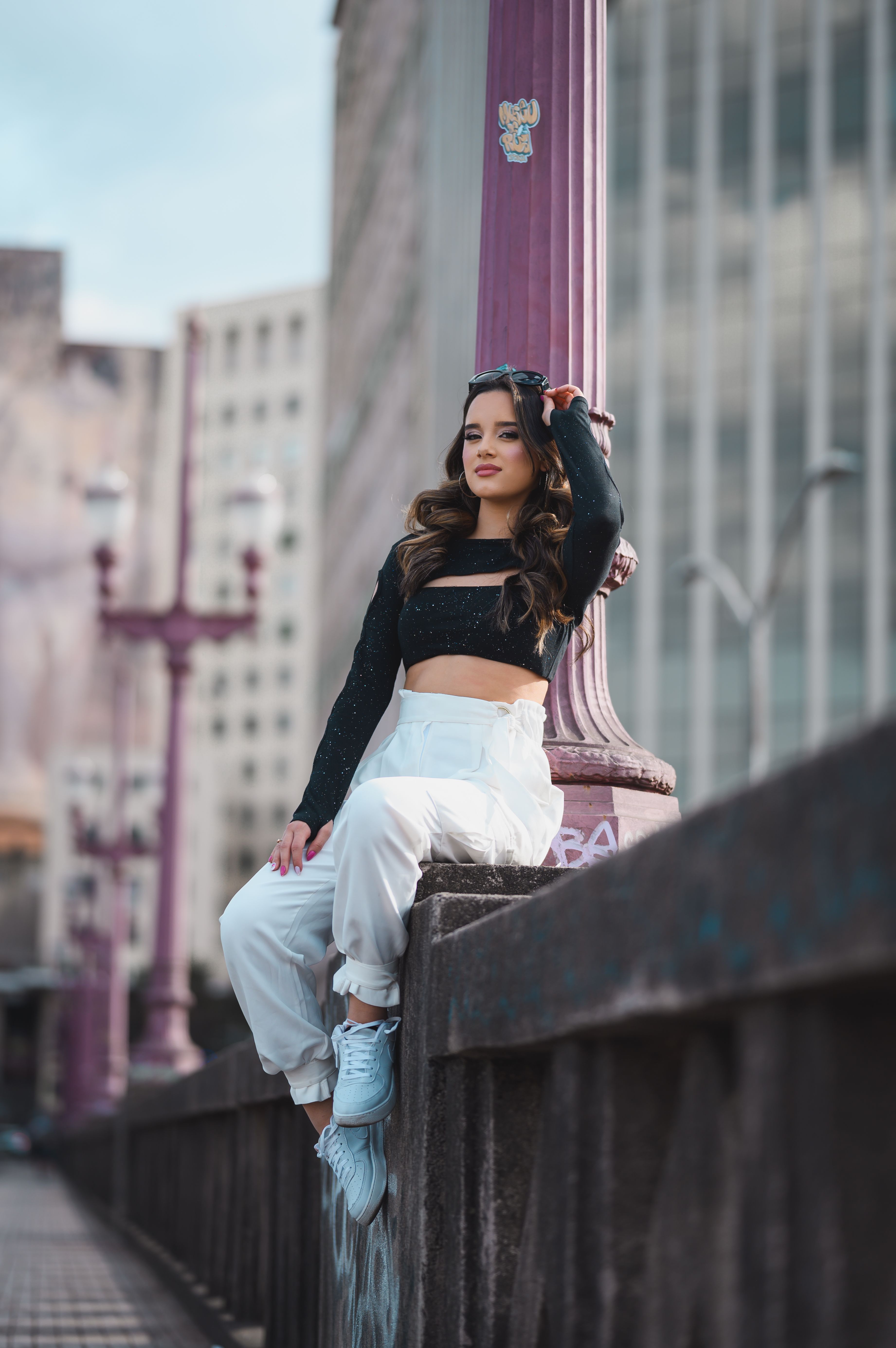 A woman in white pants and crop top sitting on a bridge · Free Stock Photo