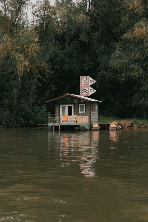 Free A serene boathouse on a river in Hungary surrounded by lush trees. Stock Photo