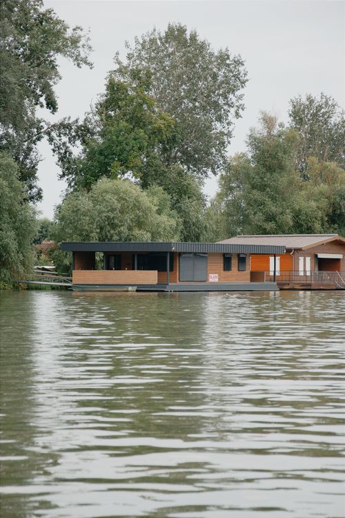 Free Peaceful house on a lake surrounded by lush trees, ideal for relaxation. Stock Photo