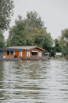 Serene lakeside house in Hungary amidst lush green trees, reflecting on calm waters, ideal for nature lovers.