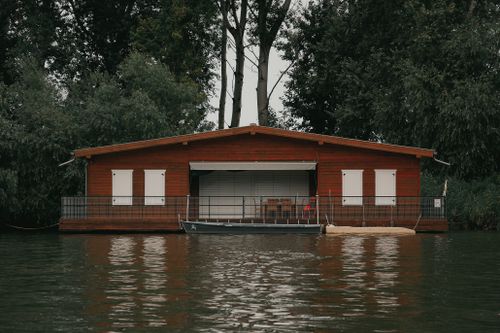 Free Serene boathouse on a calm lake in Hungary surrounded by lush greenery. Stock Photo