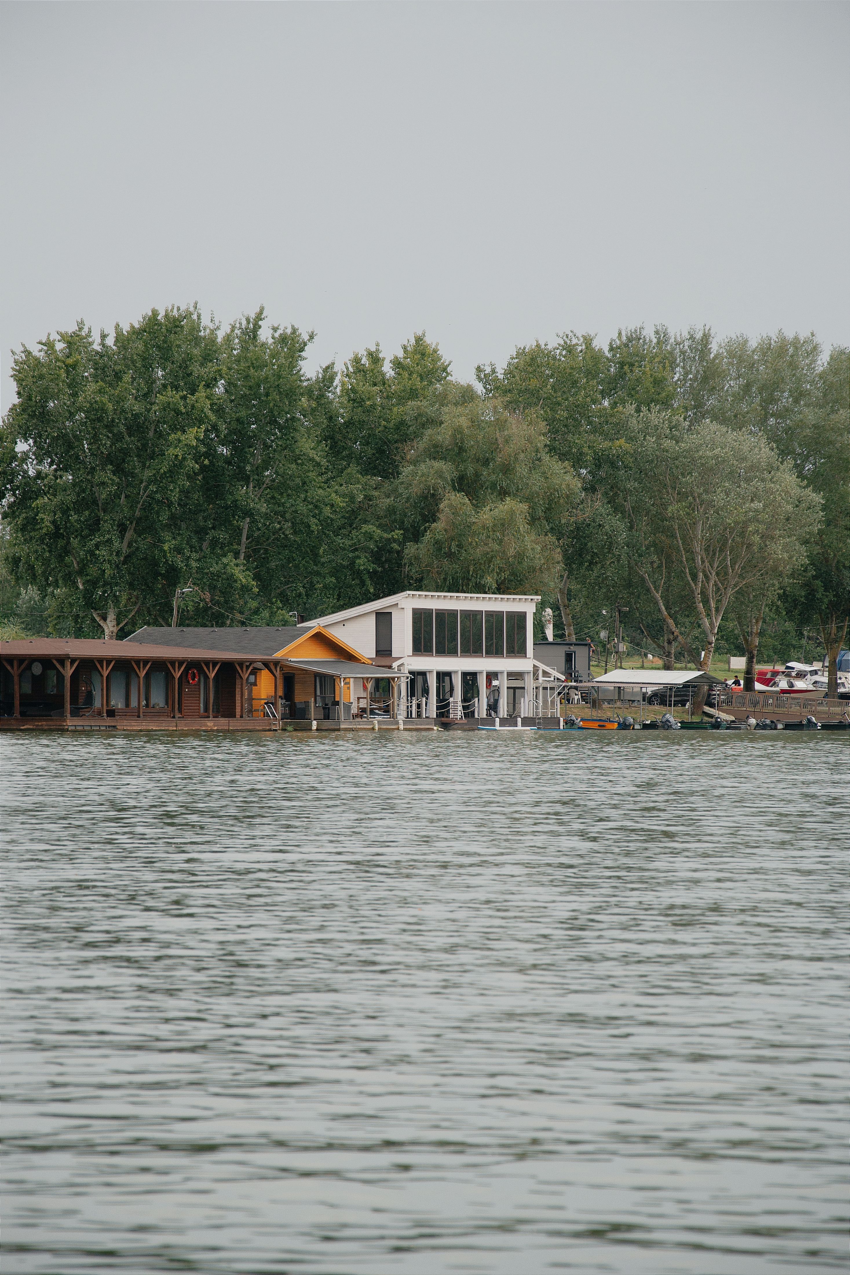 Charming lakeside house in Hungary surrounded by lush trees, ideal for serene reflections.