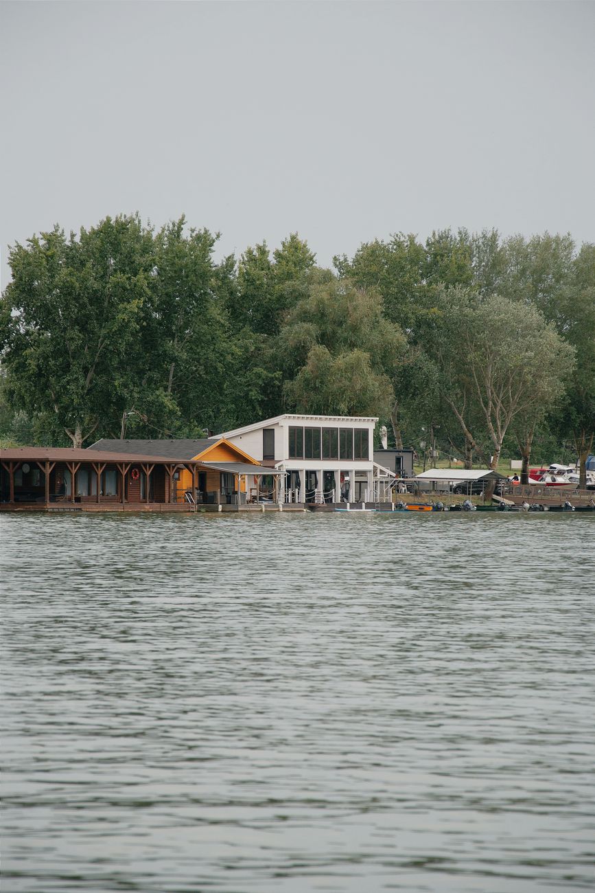 Charming lakeside house in Hungary surrounded by lush trees, ideal for serene reflections.
