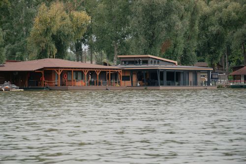 Free A modern houseboat on a tranquil lake surrounded by lush trees in Hungary. Stock Photo
