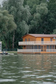 Modern wooden house by a serene lake in Hungary, surrounded by lush greenery.