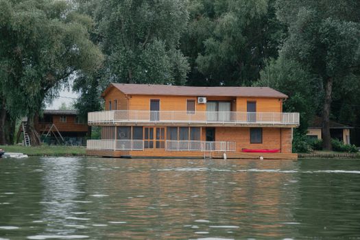 A picturesque wooden house floating on a tranquil lake surrounded by lush greenery in Hungary.