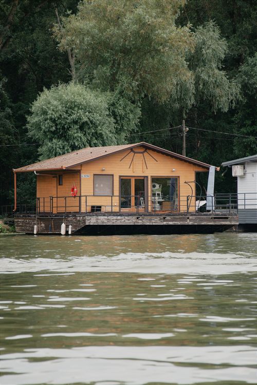 Free A peaceful wooden house on a Hungarian river surrounded by lush greenery. Stock Photo